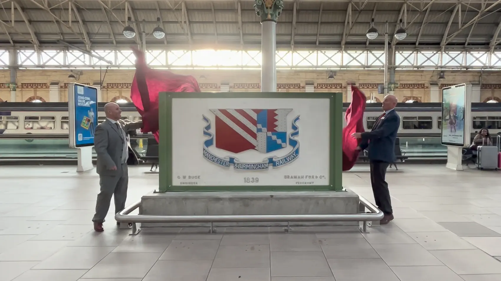 two men beside a plaque at a station
