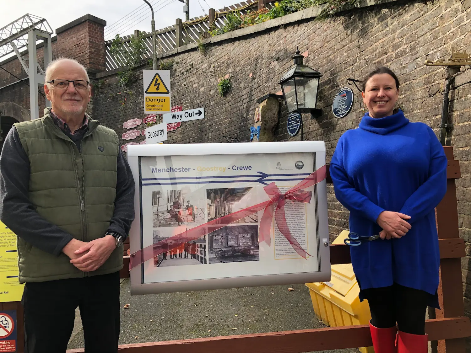 two people standing by a history board at a station